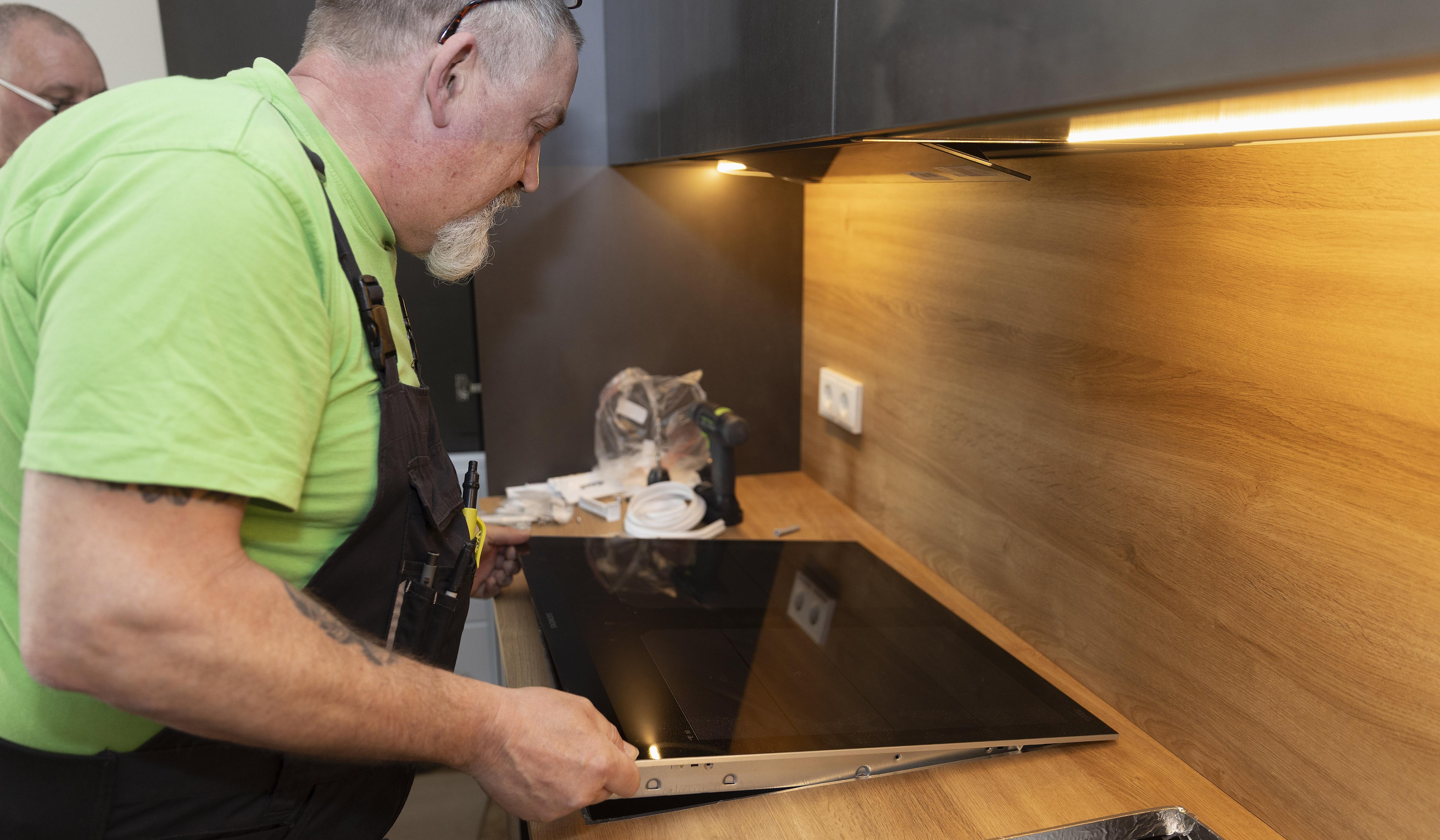 Handwerker installiert ein Kochfeld in einer modernen Küche