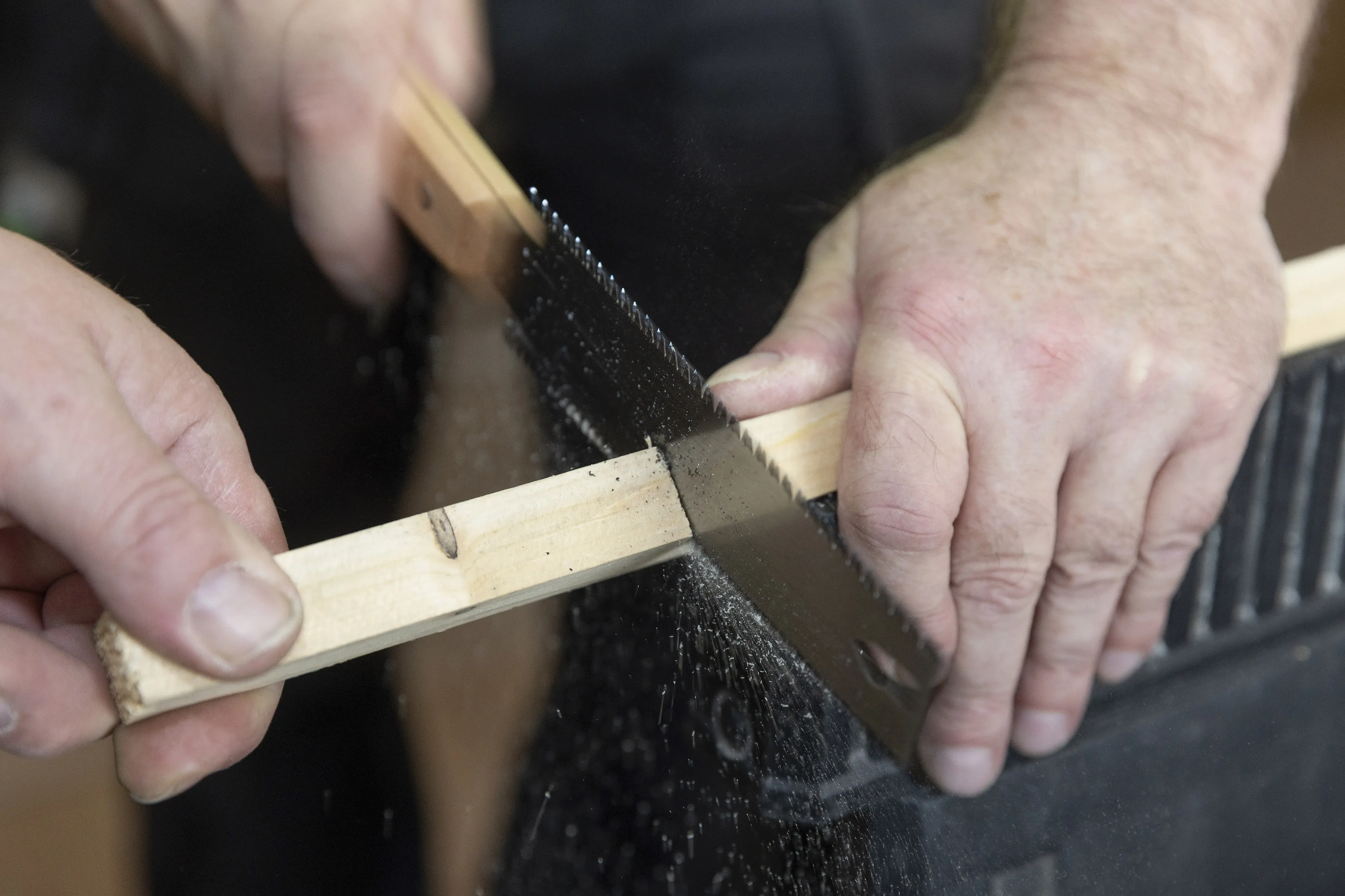 Hand sägt ein Holzstück mit einer feinen Säge.