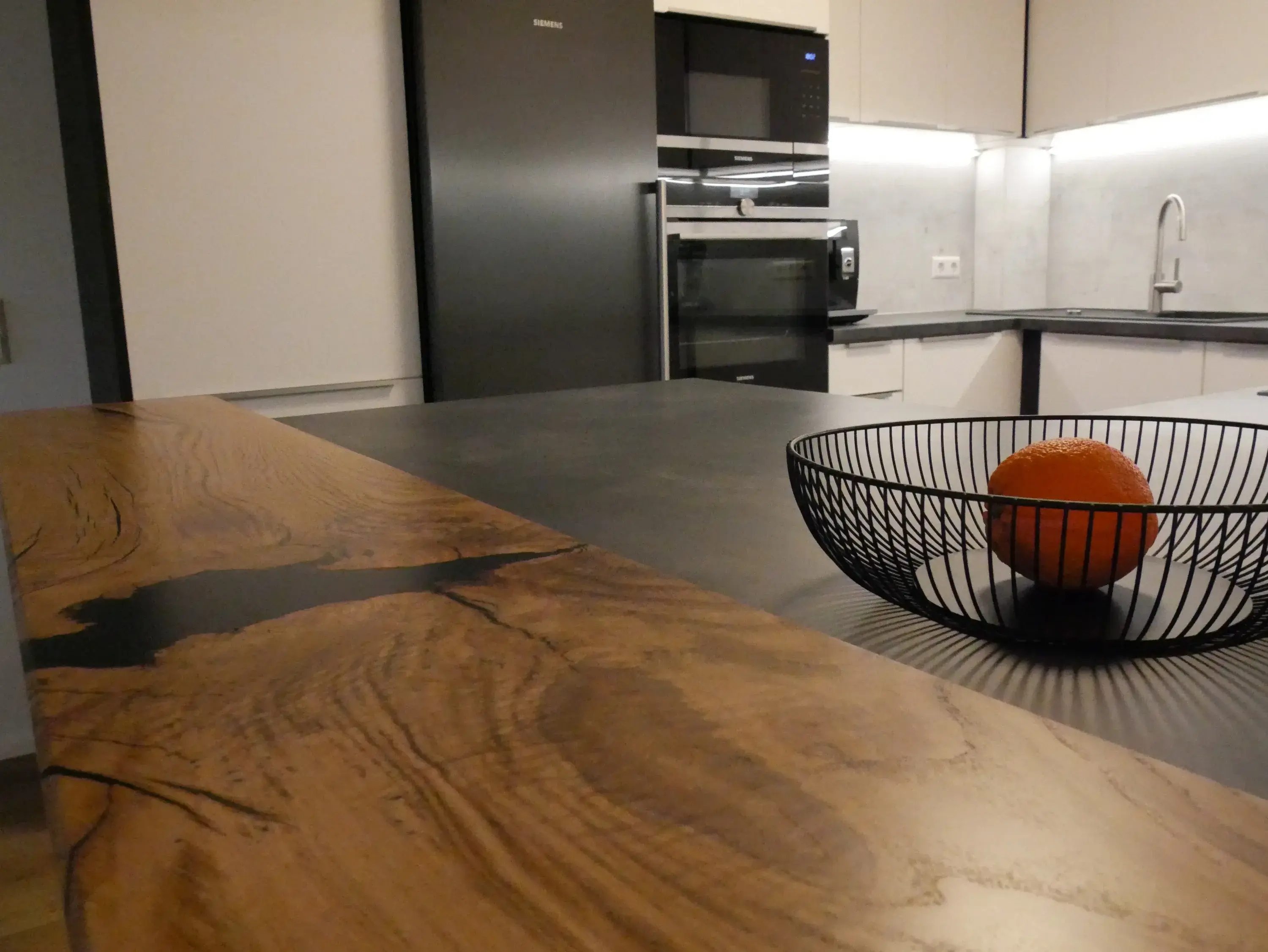 Moderne Küche mit Holztresen und einem Drahtkorb mit oranger Frucht